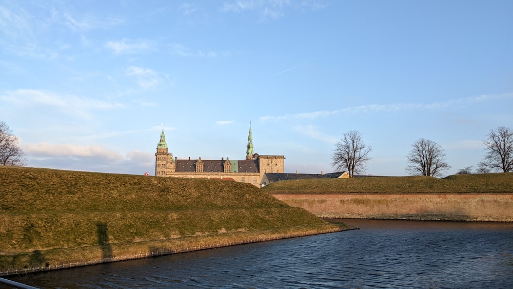 a castle with towers on top of a hill next to a body of water