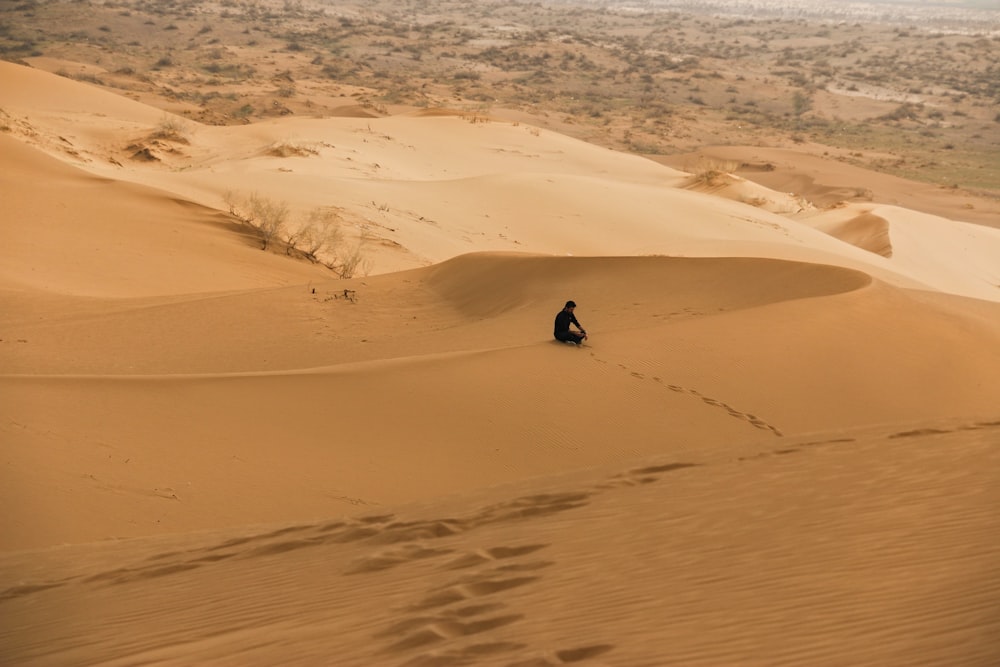 a person sitting in the middle of a desert