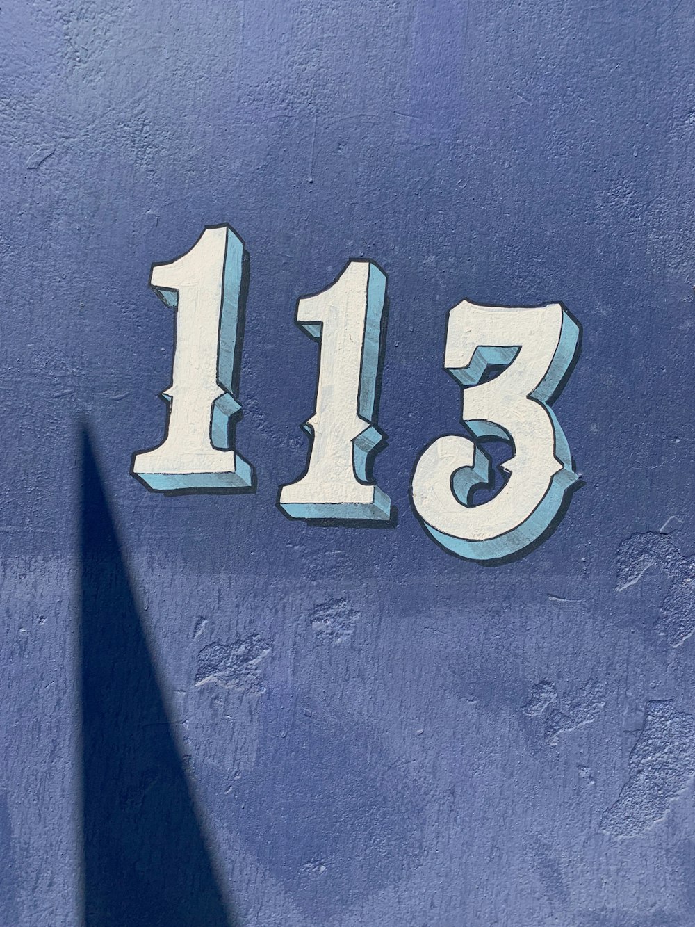 a close up of the number thirteen on a blue wall