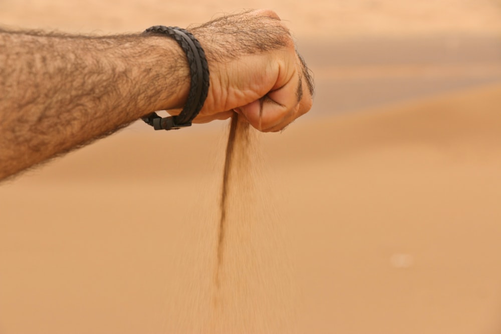 a hand is sprinkling sand on a beach