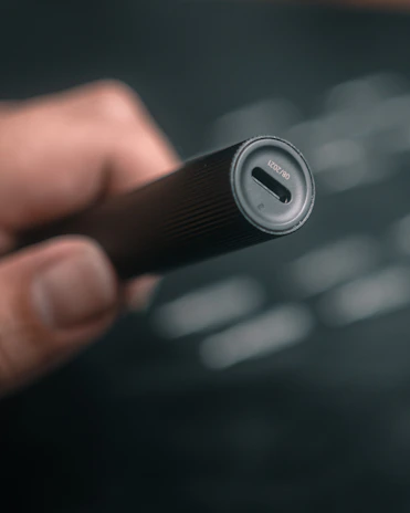 Close-up of a hand holding a sleek USB-C rechargeable AA battery glowing softly.