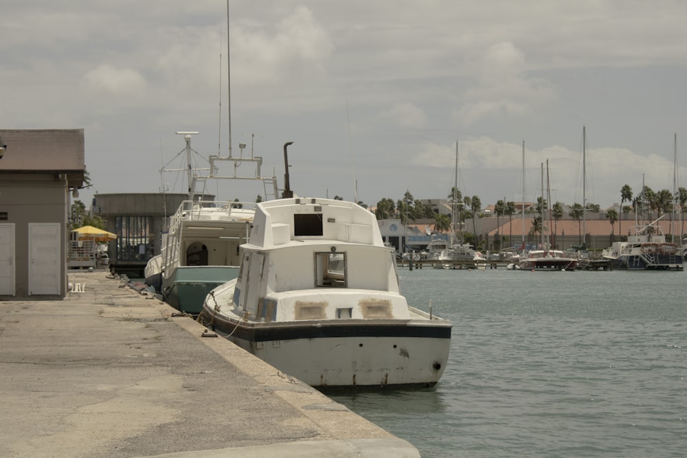 a white boat is docked at a dock