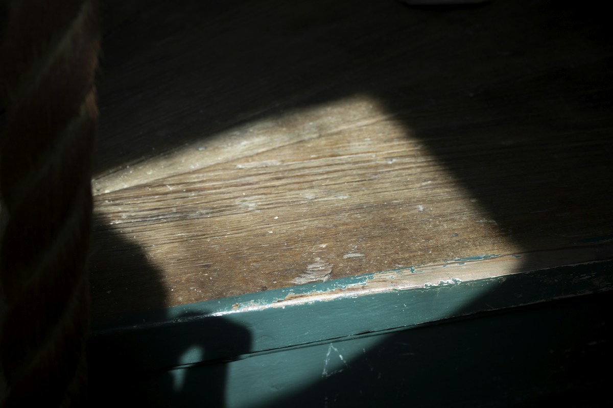 Shadow of a person on a wooden floor, illustrating a reflective moment during an educational field trip.