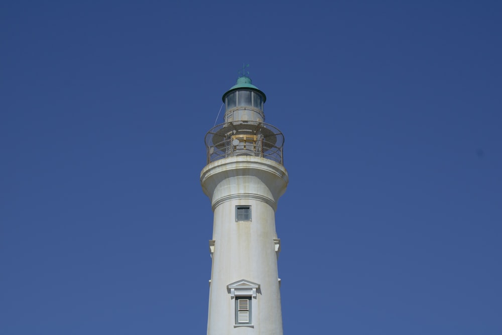 a white lighthouse with a green top against a blue sky