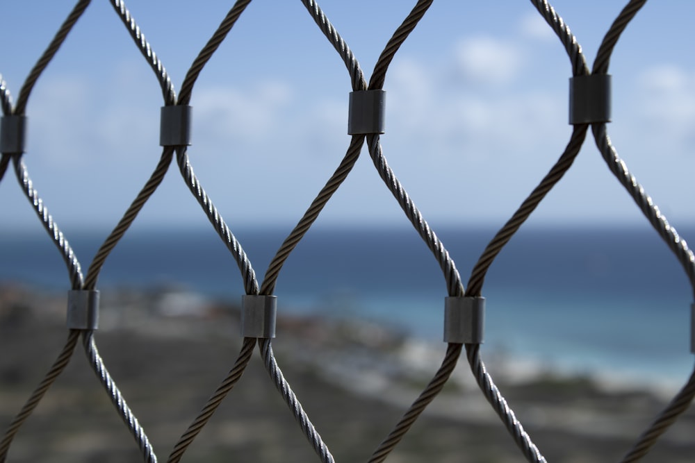 a close up of a fence with a view of the ocean