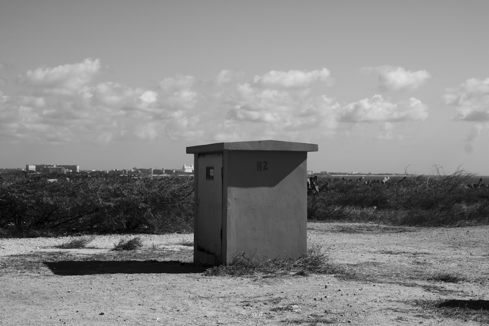 a small outhouse sitting in the middle of a field