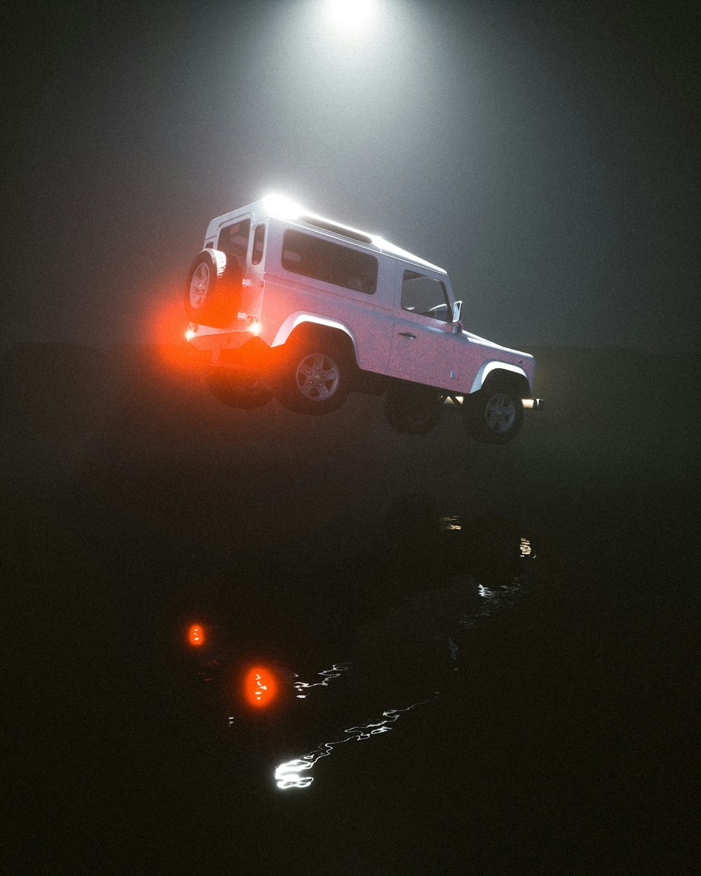 a white jeep driving down a road at night