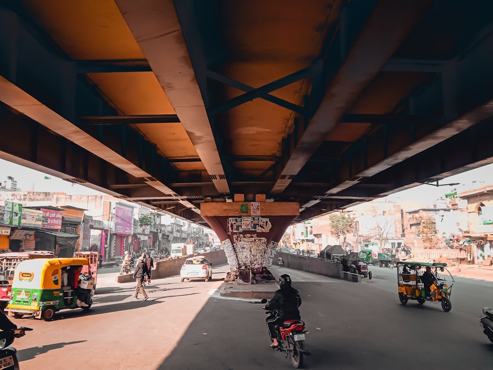 a man riding a bike down a street under a bridge