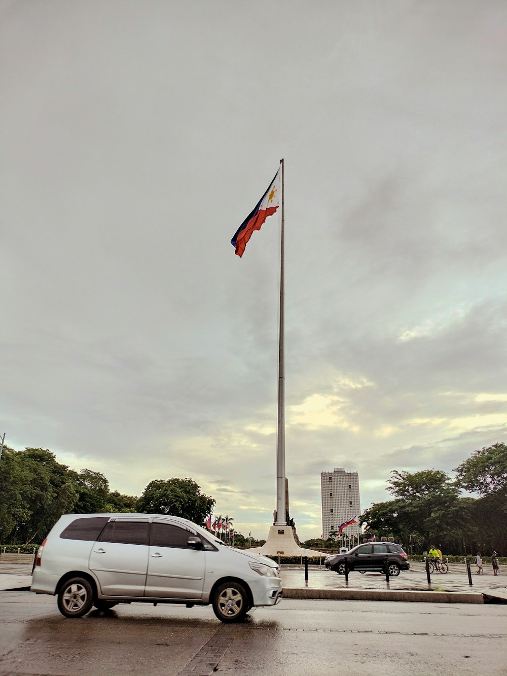 a white car parked in front of a flag pole