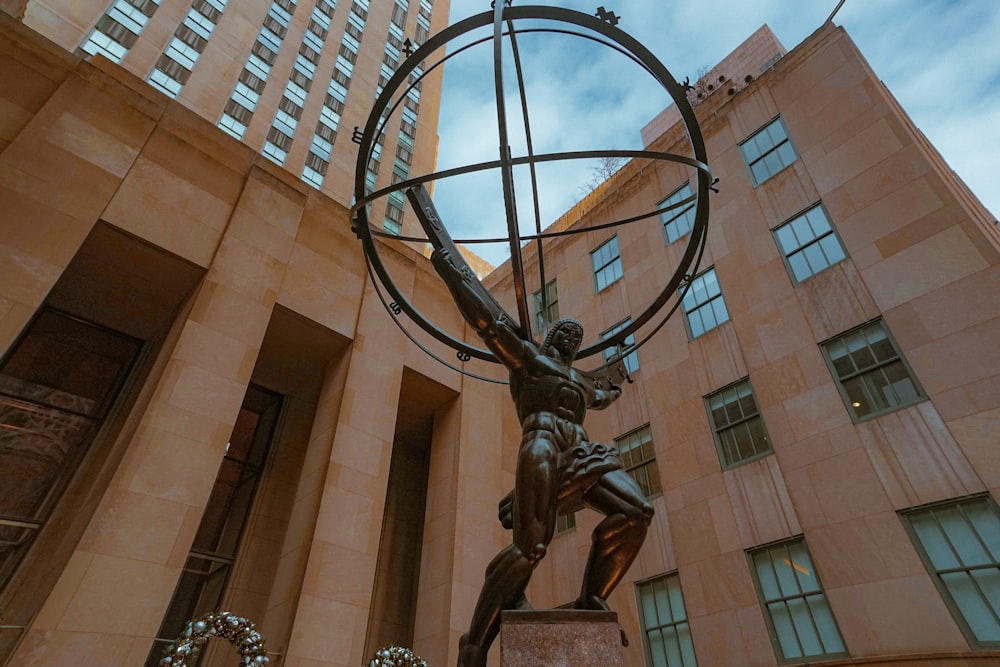 a statue of a man holding a globe in front of a building