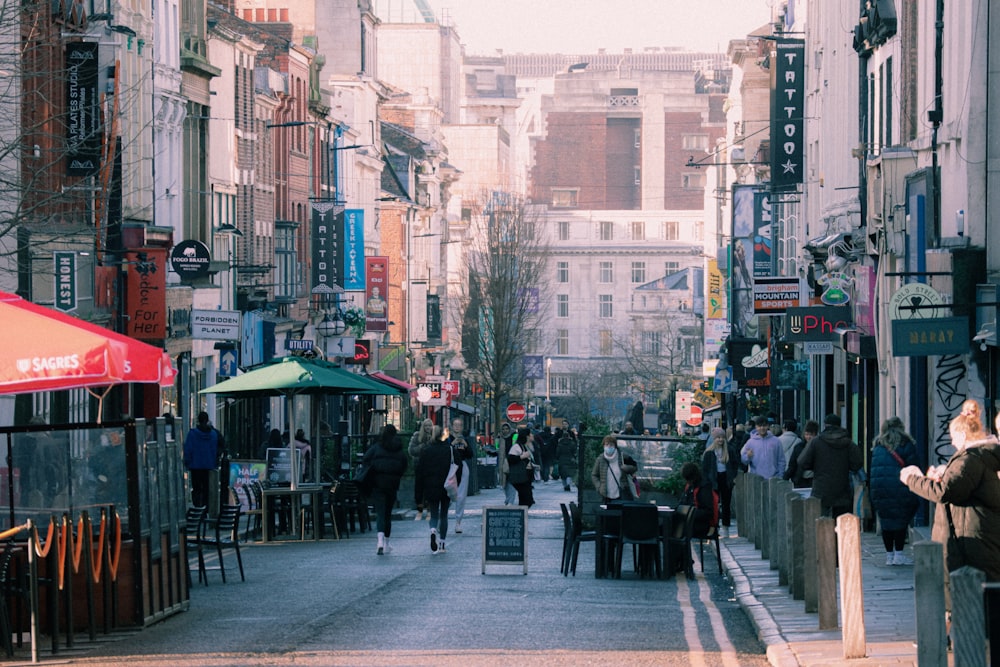 a group of people walking down a street next to tall buildings