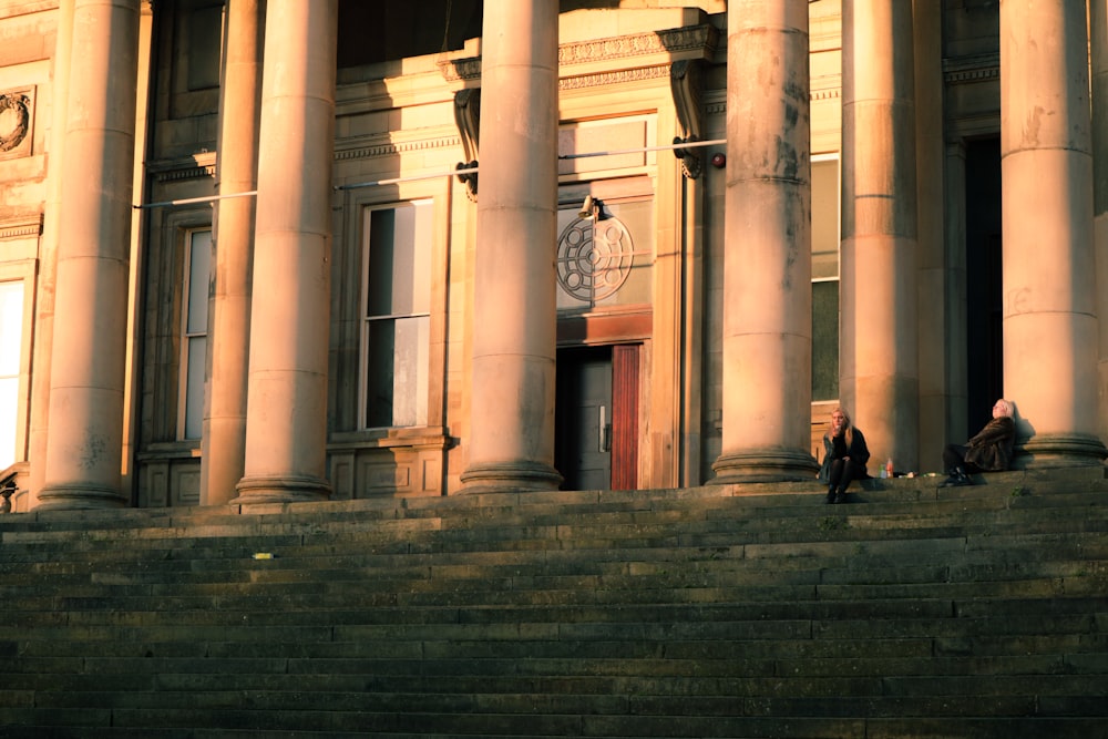 two people sitting on the steps of a building