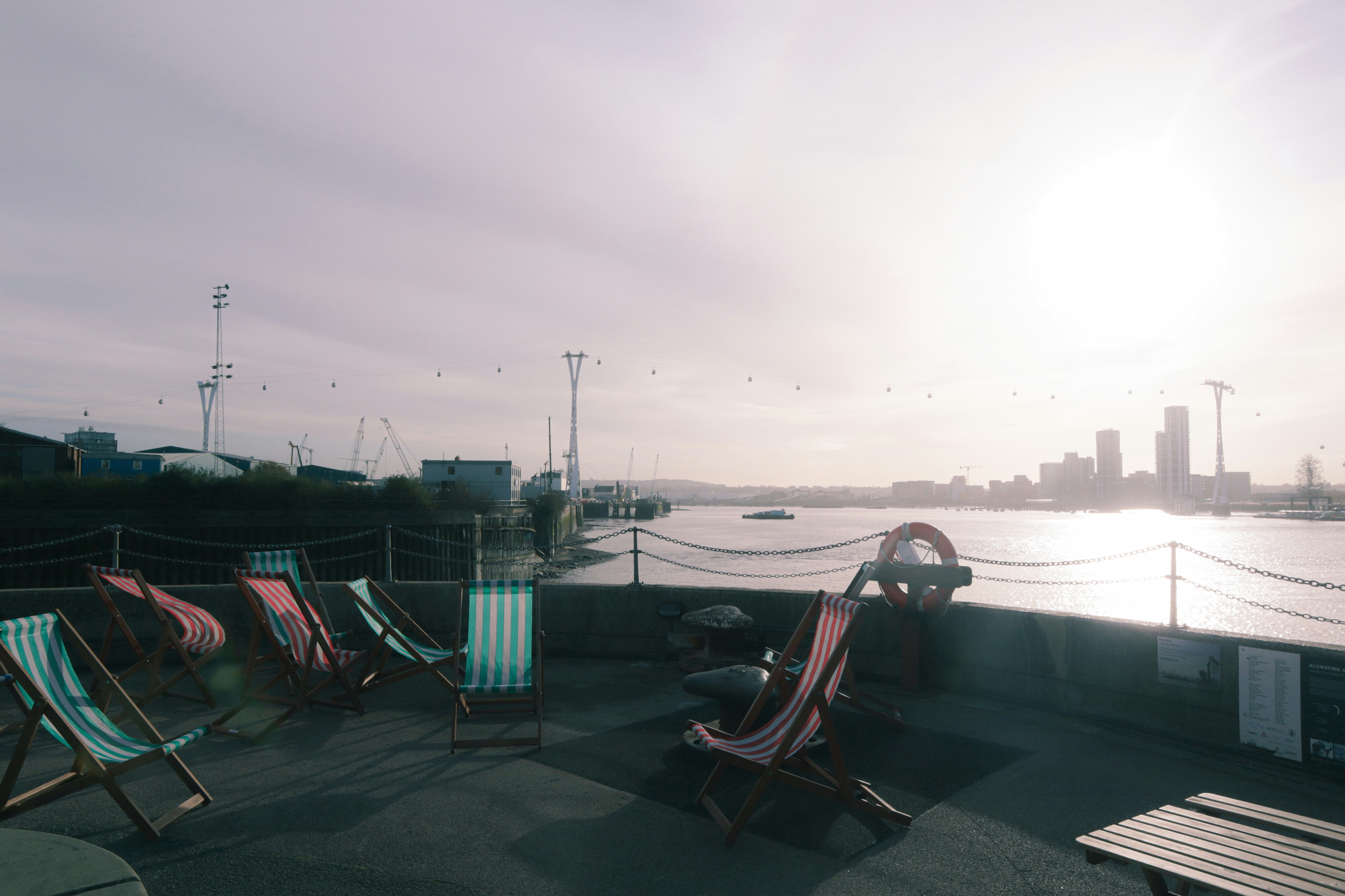 a row of lawn chairs sitting next to a body of water