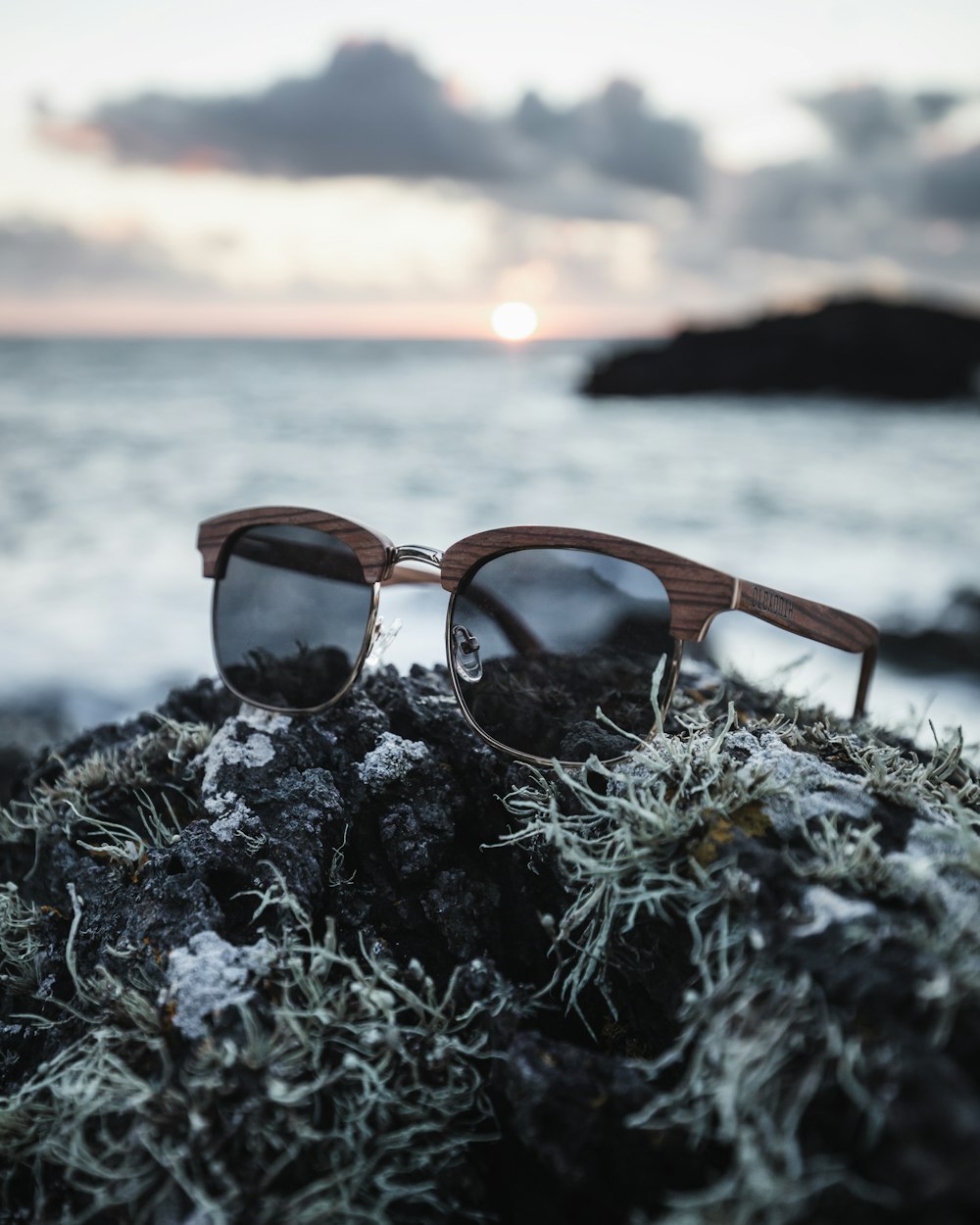 a pair of sunglasses sitting on top of a rock