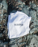 A black t-shirt laid flat on a white surface, featuring a minimalist poetic quote in English