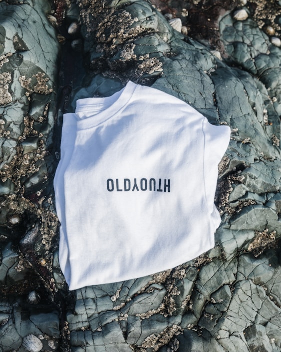 Close-up of a black rock band t-shirt with bold white lettering and red accents on a dark background