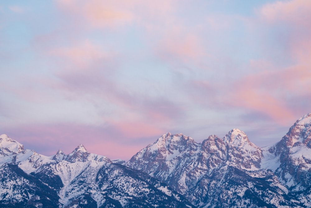 the mountains are covered in snow as the sun sets