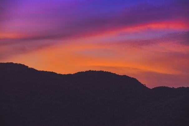 Airbrushed t-shirt featuring a mountain sunset design with vibrant colors.