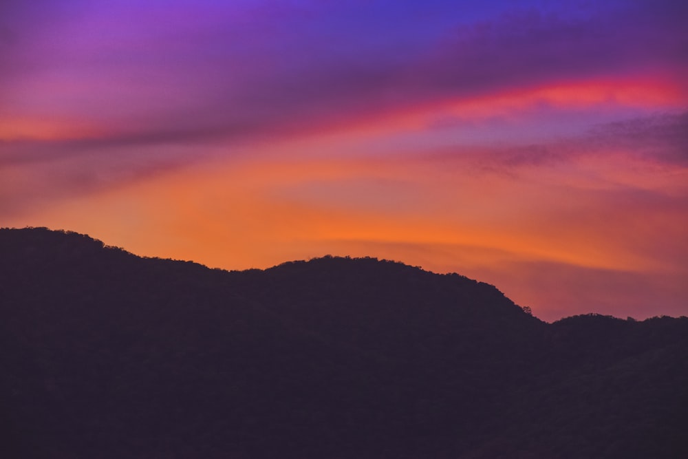 a sunset with a mountain in the background