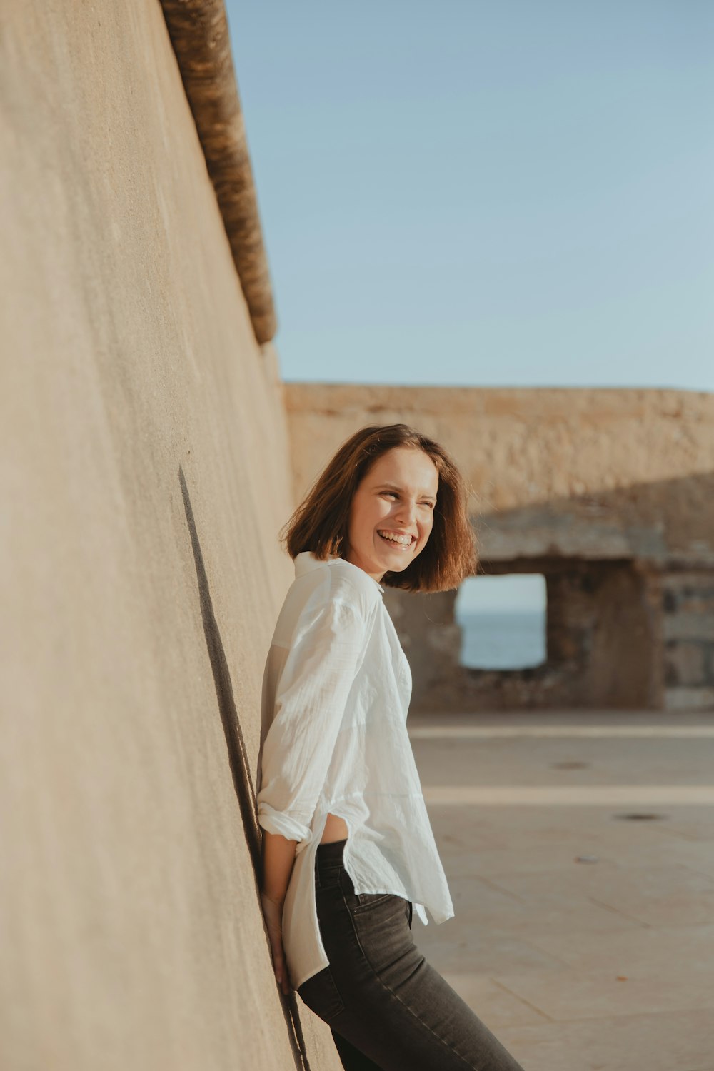 a woman leaning against a wall with a smile on her face