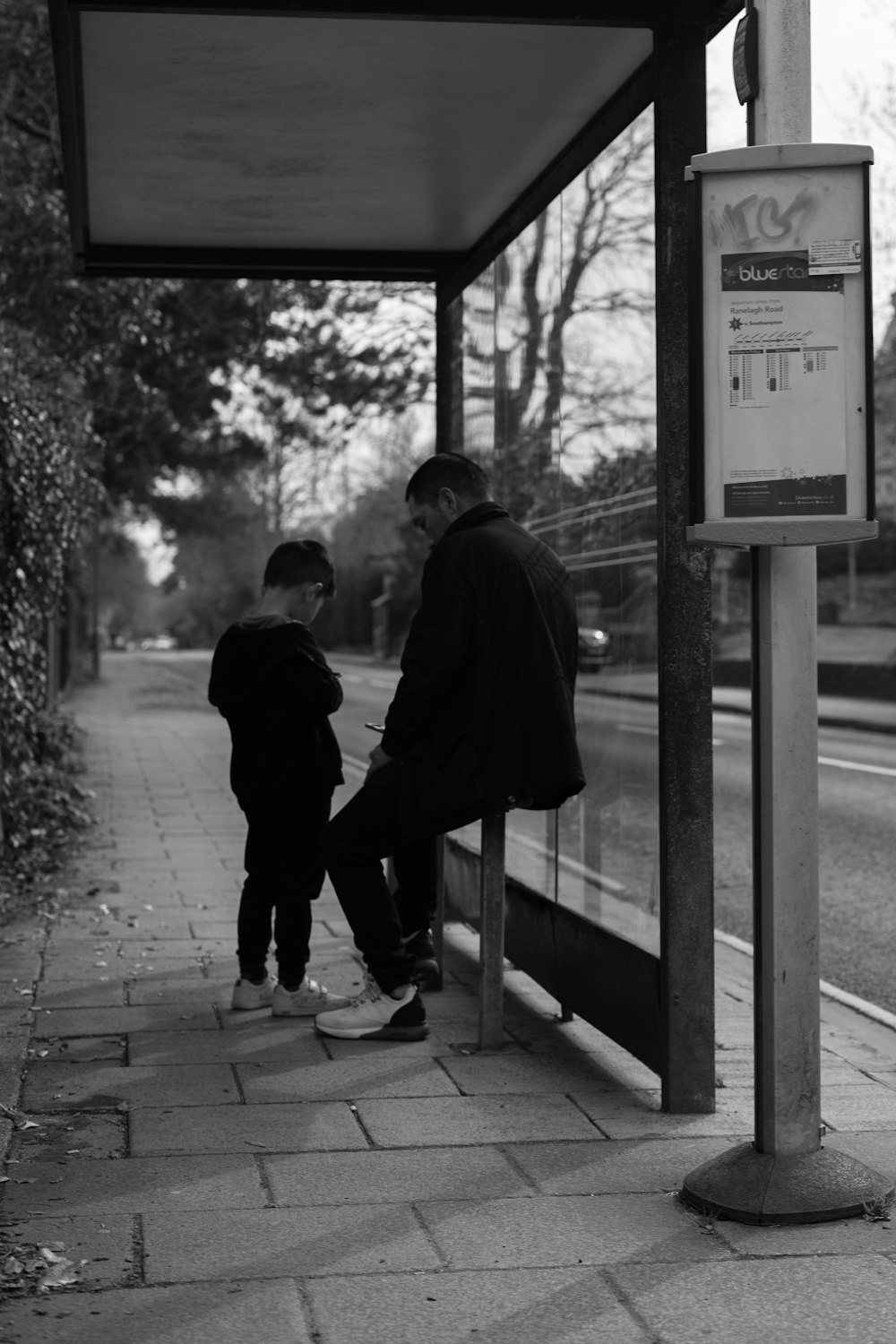 a man standing next to a little boy near a bus stop
