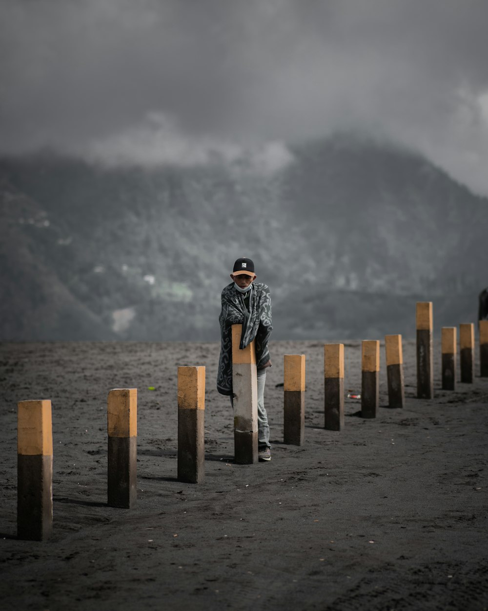 a man standing next to a row of wooden poles