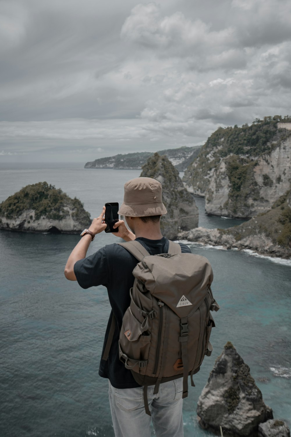 a man taking a picture of the ocean with a cell phone