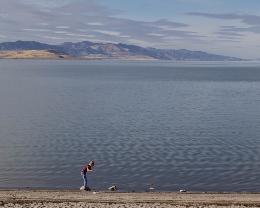 Une femme debout sur une plage à côté d’un plan d’eau