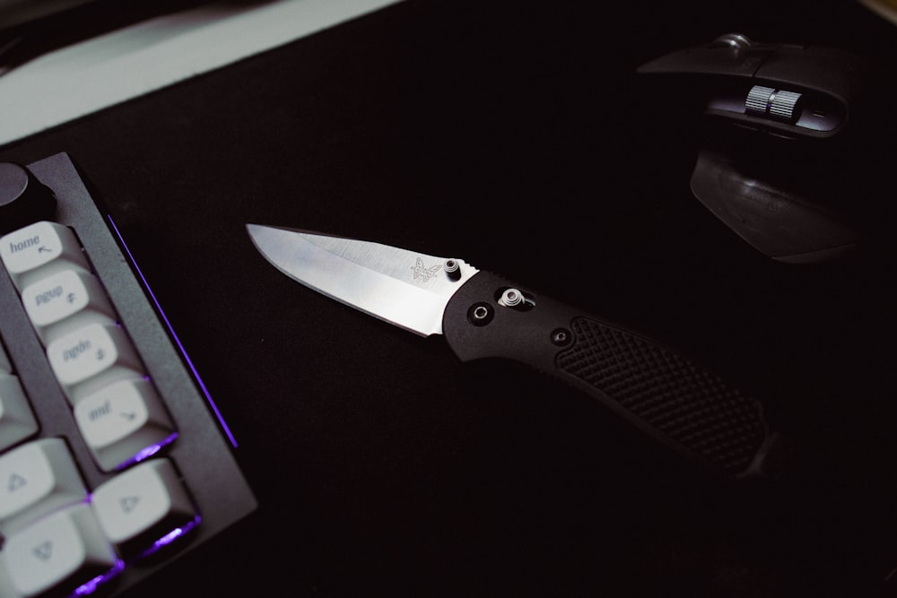 a knife sitting on top of a table next to a keyboard