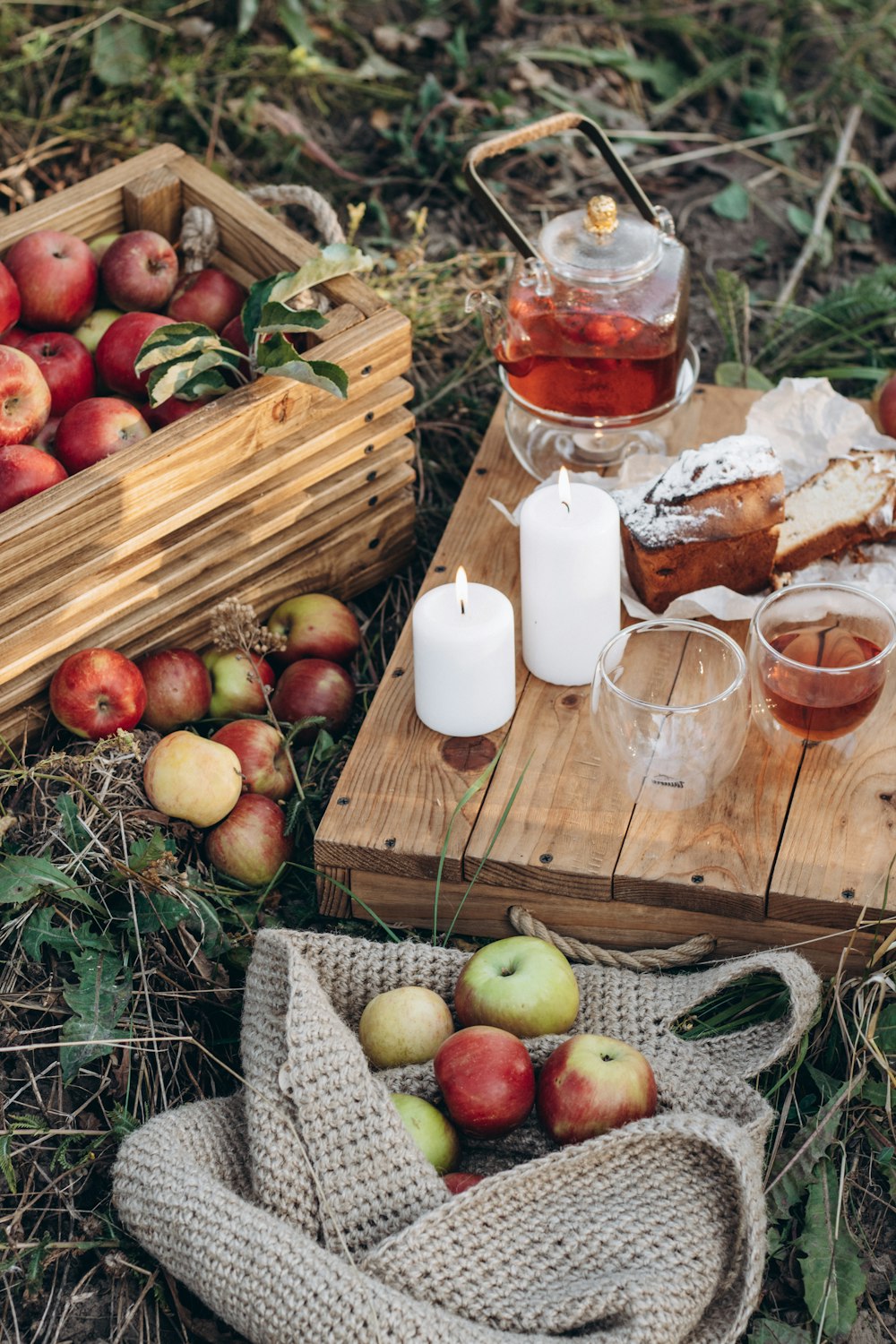 a wooden tray topped with apples next to a basket of apples