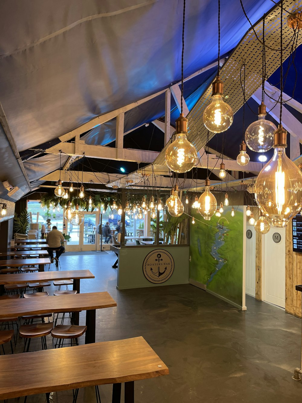 a restaurant with wooden tables and hanging lights