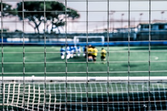 Close-up of green PVC coated sports fence tightly woven around a soccer field.