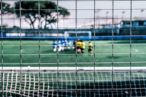 Close-up of green PVC coated sports fence tightly woven around a soccer field.