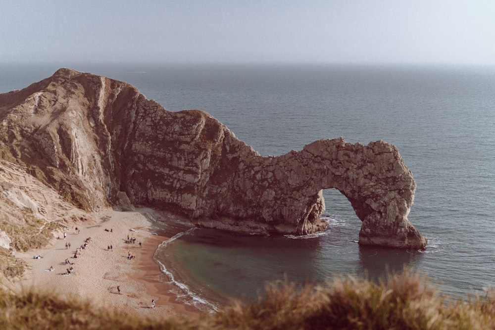 a beach with a large rock formation in the middle of it