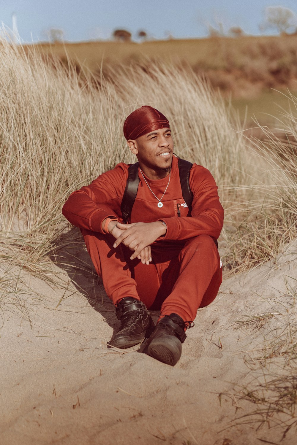 a man in a red outfit sitting on a beach