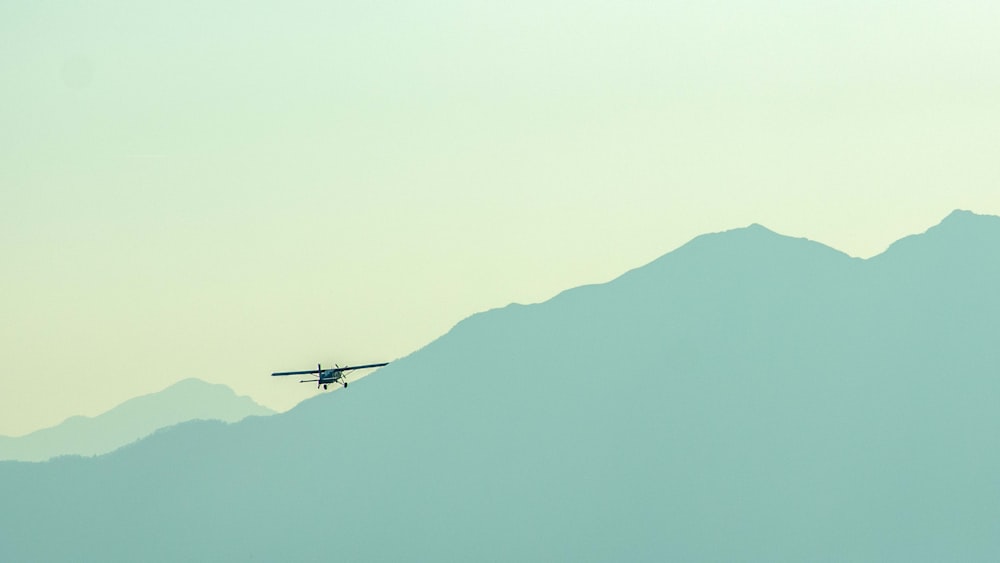 a small plane flying over a mountain range