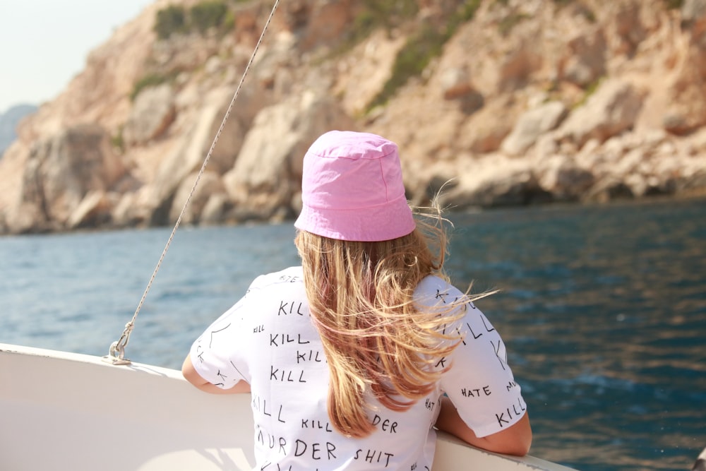 a girl in a pink hat is sitting on a boat