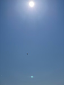 Technician inspecting a helicopter engine outdoors with clear blue sky.