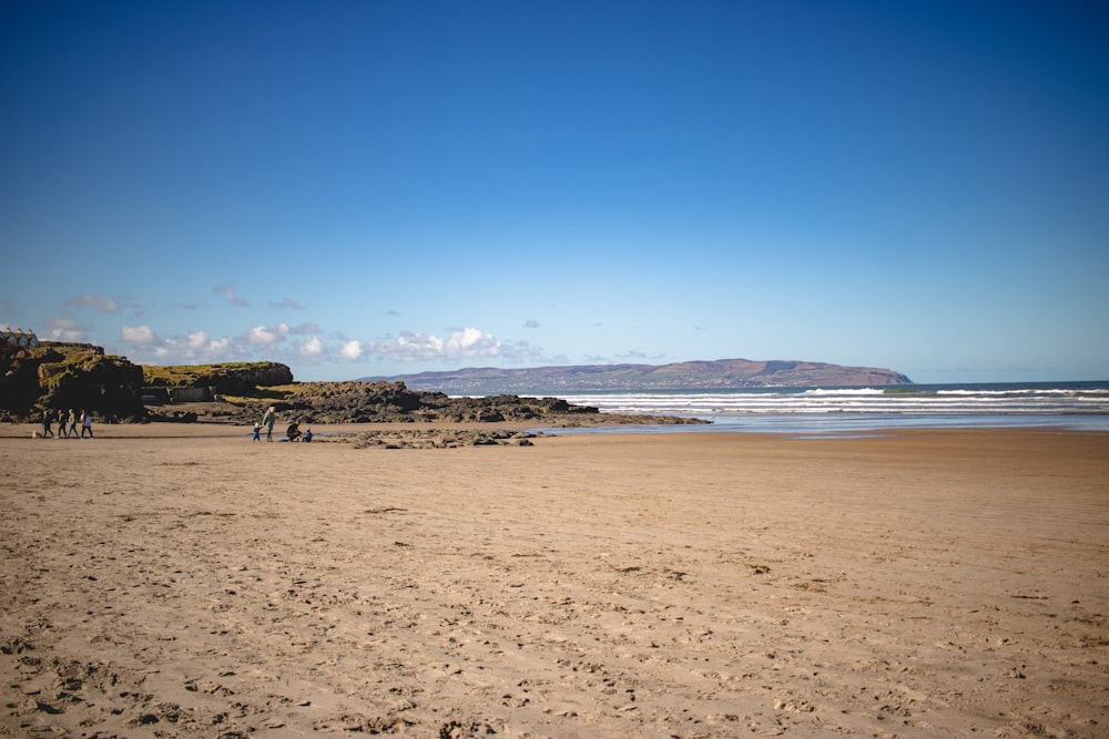 a couple of people standing on top of a sandy beach