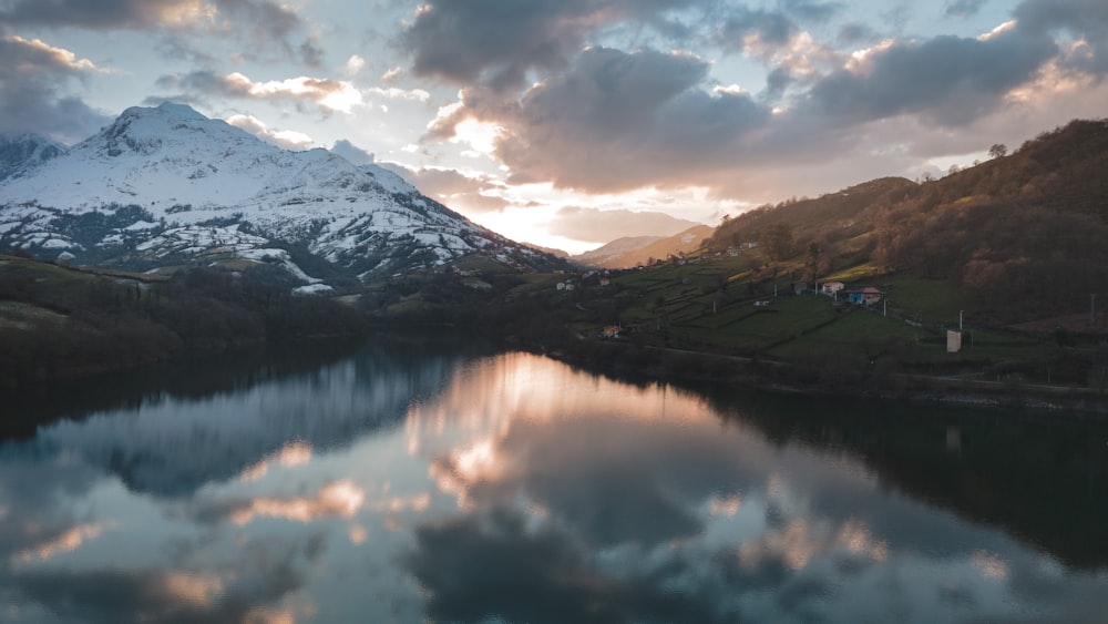 a lake surrounded by mountains under a cloudy sky