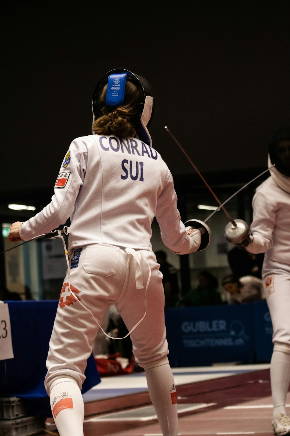 a woman in white fencing gear on a court