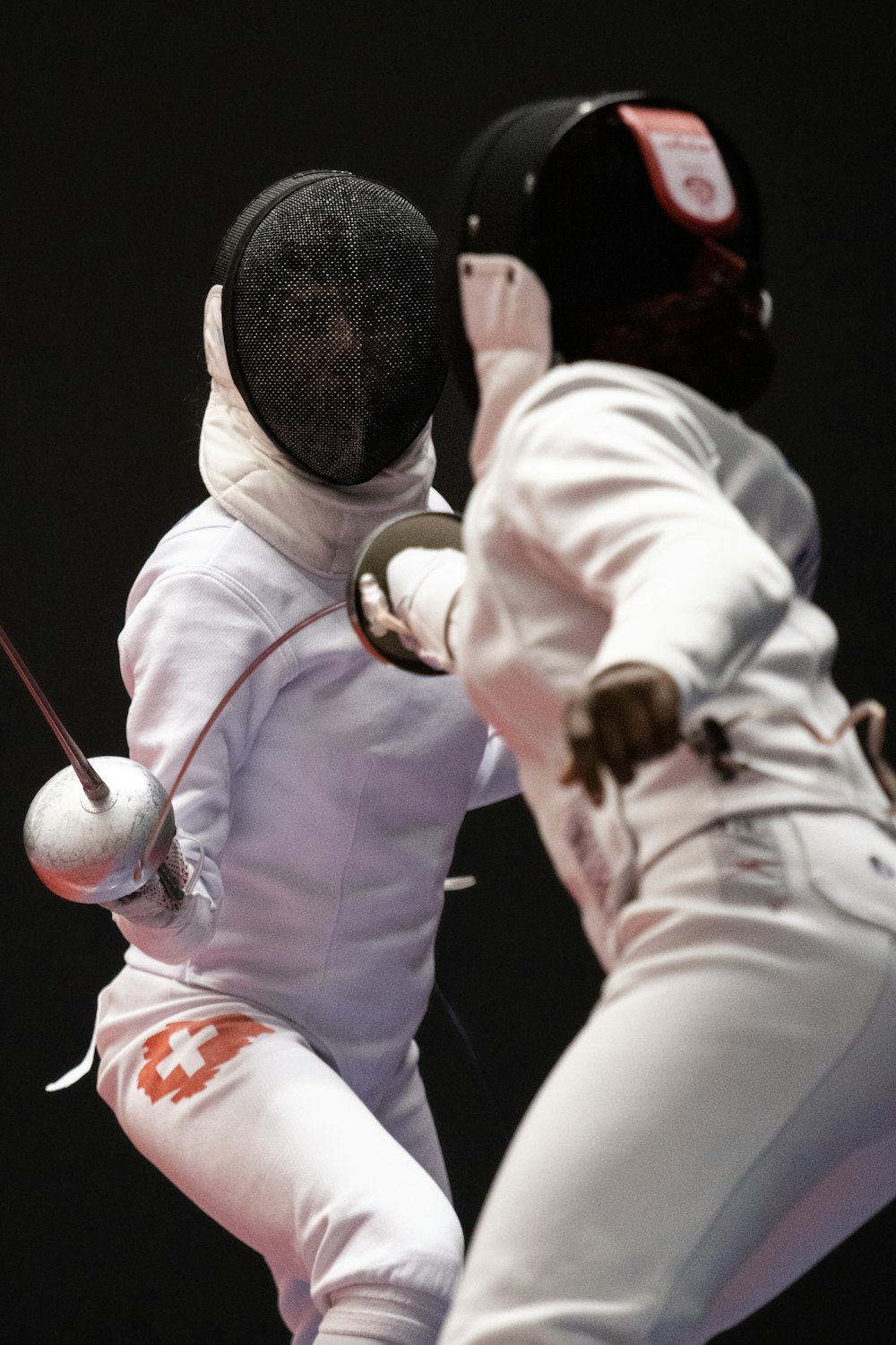 two men in fencing gear are fighting over a ball