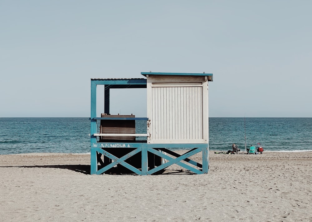 uma cabana de praia azul e branca sentada no topo de uma praia de areia