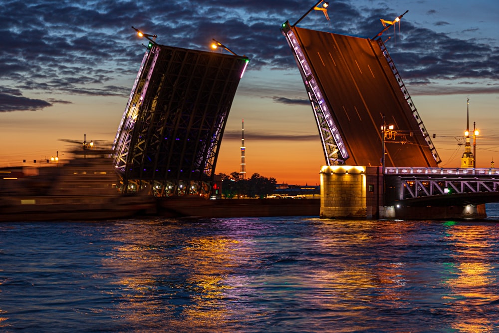 a large ship passing under a bridge at night