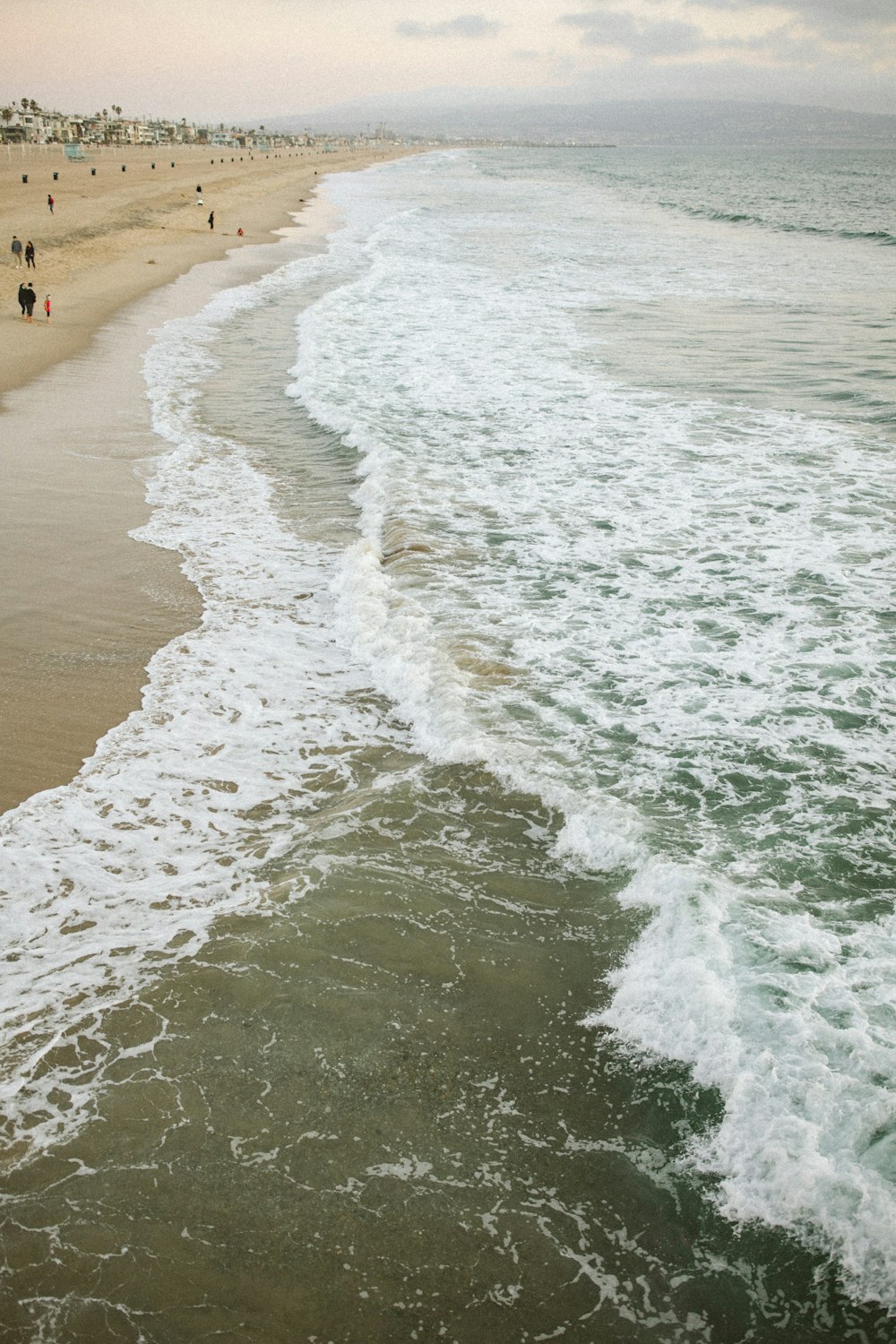 a group of people walking along a beach next to the ocean