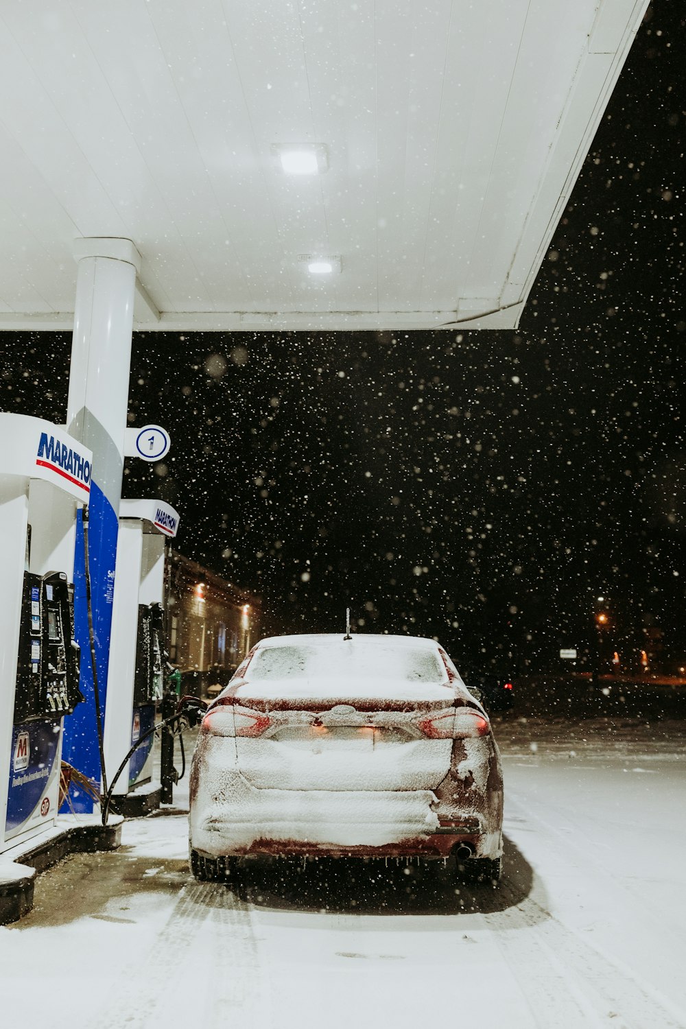 a car is parked at a gas station in the snow