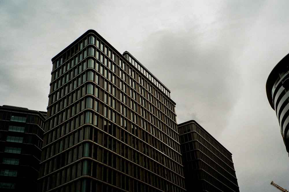 a tall building sitting next to a tall building under a cloudy sky