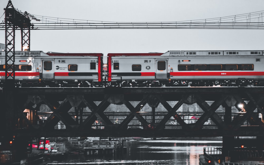 a silver and red train traveling over a bridge
