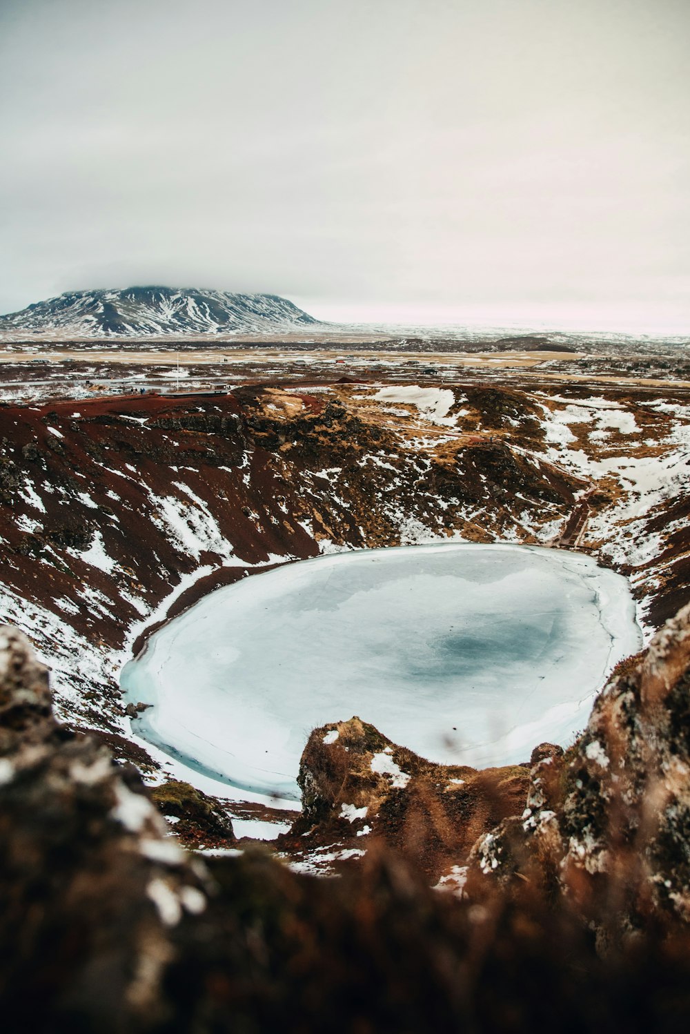 a small lake surrounded by snow covered ground