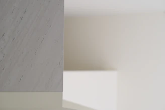 Close-up of polished white marble floor tiles reflecting soft natural light in a minimalist room.